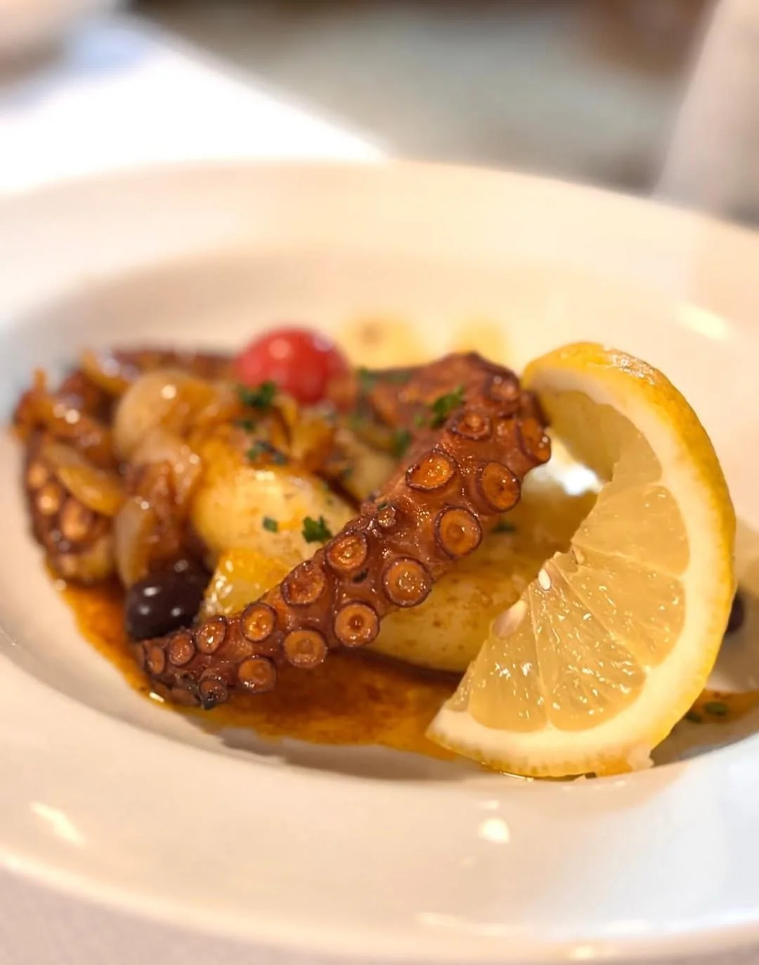 Polvo à lagareiro servido com batatas, tomates e limão siciliano.