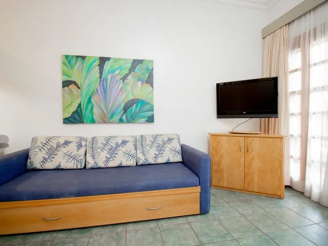 Área de estar com sofá e televisão do Quarto Standard do Ilha Flat Hotel