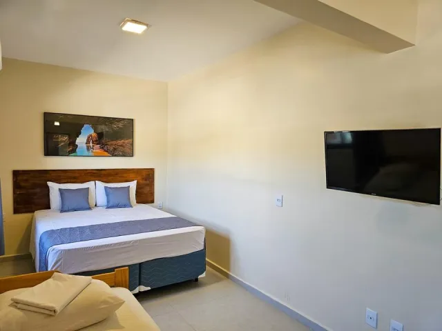 Quarto com cama de casal, cama auxiliar e televisão do Premium do Ilha Flat Hotel