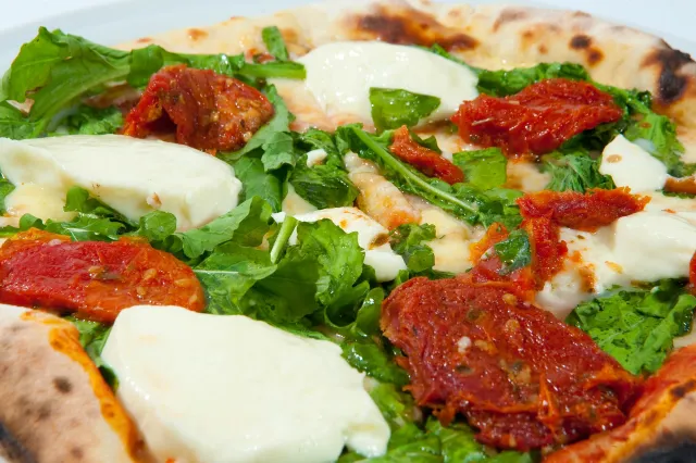 Pizza com rúcula, tomate seco e queijo