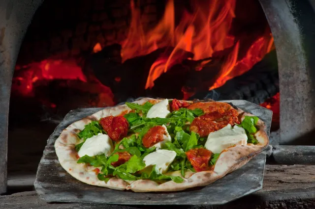 Pizza saindo do forno a lenha