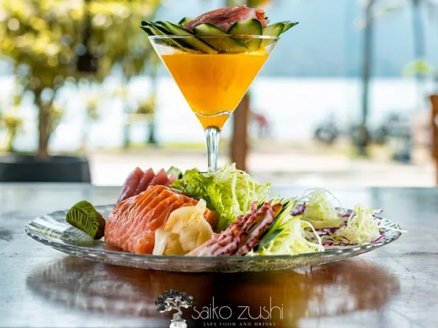 Seleção de sashimis servida com drink diante do mar
